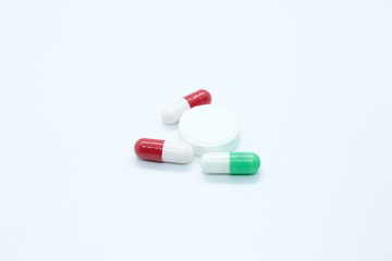 Multi-colored pill capsules are located on a white background