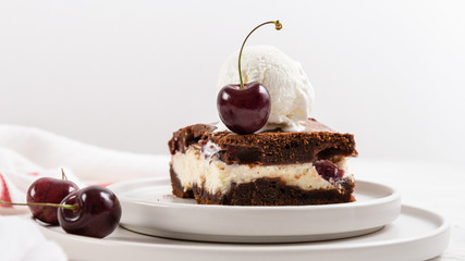chocolate brownie cake dessert with cherry and ice cream ball on the top on a white background. Copy space, side view. Homemade bakery and dessert. Bakery, confectionery concept.