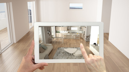 Augmented reality concept. Hand holding tablet with AR application used to simulate furniture and design products in empty interior with ceramic floor, modern white kitchen