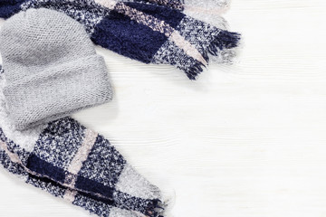 Comfort warm scarf for cold weather. Knitted grey cap on white wooden backgraund with copy space. Top view. Flat lay.