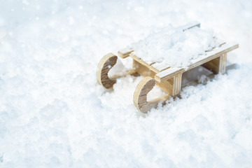 Wooden sledge on blurred snow with light, selective focus. Christmas decoration. Happy New Year 2020 poster or greeting card with copy space.