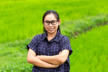 Naklejka na ściany i meble Asian farmer woman smile and cross one's arms with a look of proud on rice field background.