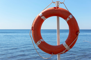 Orange lifebuoy hanging on the phone of the sea.