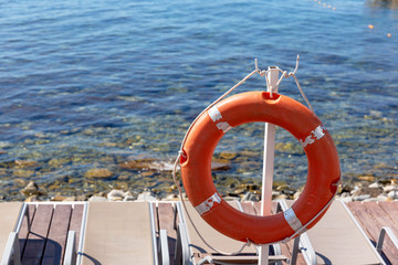 Orange lifebuoy hanging on the phone of the sea.