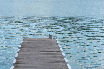 Gray-brown, wooden, pontoon, pier on the water surface of the lake.