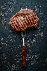  Grilled ribeye beef steak on the fork. At the aged table. Top view. Free space for your text. © Yaruniv-Studio