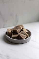 Portion of halva with vanilla and sunflower seeds on marble background with copy space