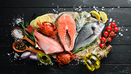 Seafood on a black wooden background. Banner Top view. Free space for your text.