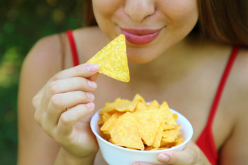 Close up portrait of woman eating tortilla chips with a full bowl in her hand.