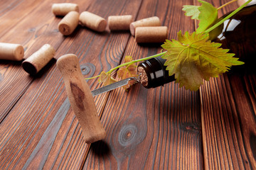Corkscrew and bottle of wine on the board - Image