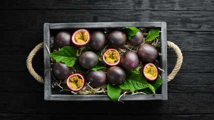 Fresh passion fruit with leaves in Wooden Box. Tropical Fruits. Top view. Free space for text.