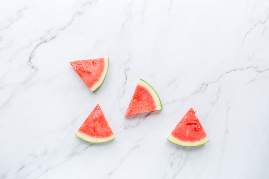 Creative flat lay top view of fresh watermelon slices on white marble background with copy space. Minimal summer fruits pattern for blog or recipe book. Healthy food and diet concept.