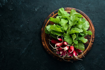 Fresh radish on a black stone background. Red radish Top view.