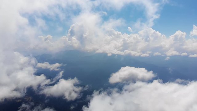 Flying through amazingly beautiful cloudscape. Picturesque timelapse of white fluffy clouds moving softly on the clear blue sky in pure sunshine. Direct view from the cockpit.