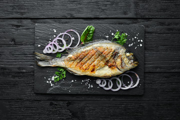 Dorado fish grilled on stone plate. Top view. Free copy space.