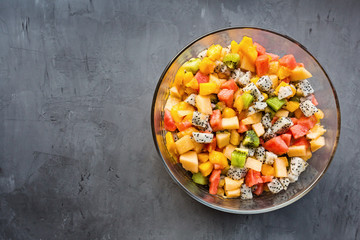 Fresh salad with exotic fruits closeup - papaya, mango, pineapple, passion fruit, dragon fruit, grapes, lichee, kiwi, melon. flat lay, overhead. Mockup, copy space, Top view.