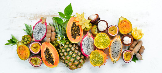 Tropical fruits on a white background: papaya, mangosteen, cactus fruit, pytahaya, pineapple. Top view. Free space for text.