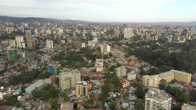 Retreating aerial footage flying over residential neighborhood in Addis Ababa, with tree filled streets and various types of homes, capital city of Ethiopia 