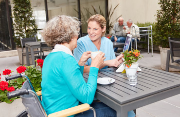 Pflegehilfe im Gespräch mit Seniorin im Altersheim