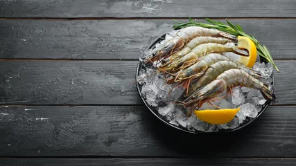 Zelfklevend Fotobehang black tiger prawns with lemon on ice. Seafood. Top view. On a black background. Free copy space. © Yaruniv-Studio