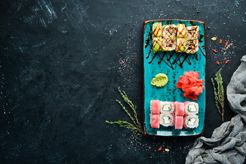 Sushi and rolls on the plate. Top view. Free space for your text. On a black background.