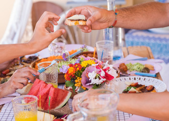 Sharing food with the family. Caucasian peoples enjoying brunch or meal together. Fruits and vegetables on the wooden table. Sunlight outdoor on the terrace