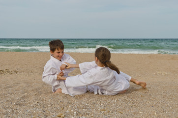 Kids practicing Aikido on the beach. Healthy lifestyle and sports concept