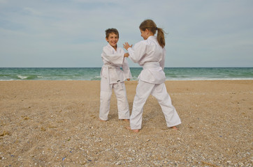 Kids practicing Aikido on the beach. Healthy lifestyle and sports concept