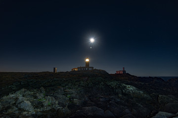 Fotografía nocturna con luna llena en el faro de Corrubedo Galicia España