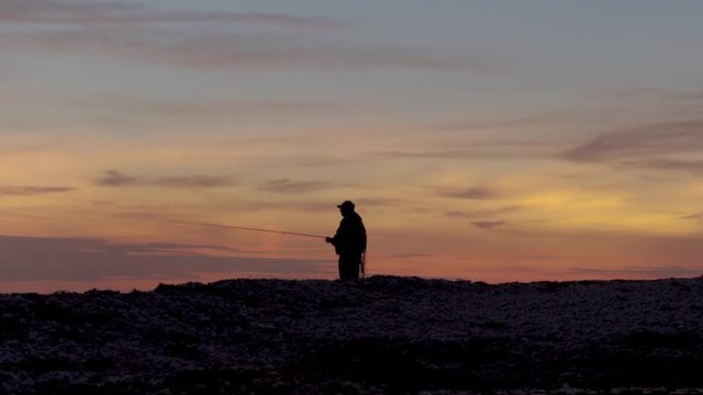 Silhouette of a man casting a fishing rod on Langeland Island.