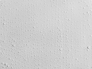 Rain water drops on a smooth white wall. Close up
