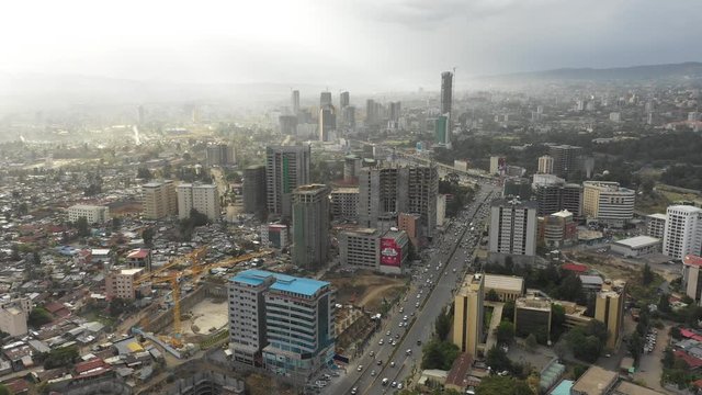 Retreating drone shot of traffic driving past construction sites and towers of Addis Ababa skyline, capital city Ethiopia Africa