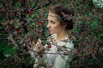 Attractive young woman enjoying her time outside in park with flowering tree in background.