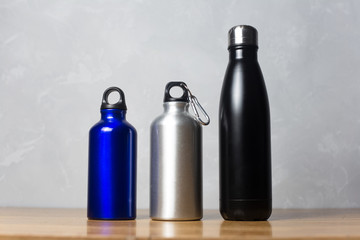 Different thermo bottles on wooden table
