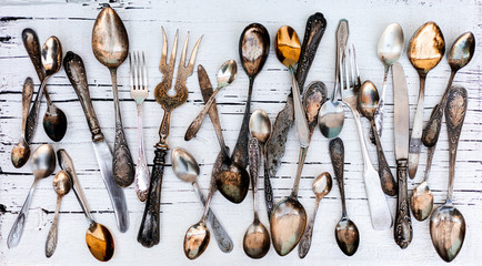 Vintage cutlery - spoons, forks and knives on an old wooden background.