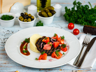 Meat cutlet with mashed potatoes and tomatoes. Restaurant serving.