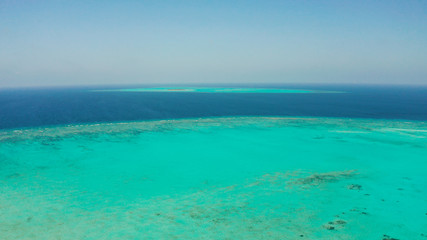 Obraz premium Tropical coral atoll with turquoise water against the sky with clouds top view. Summer and travel vacation concept. Balabac, Palawan, Philippines