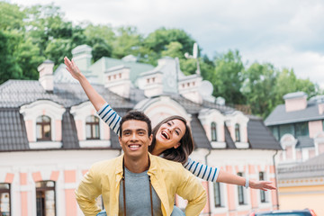 happy girl with outstretched hands near handsome mixed race man