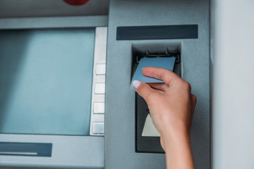 cropped view of woman putting credit card into atm machine