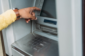 cropped view of mixed race man pressing button on atm machine