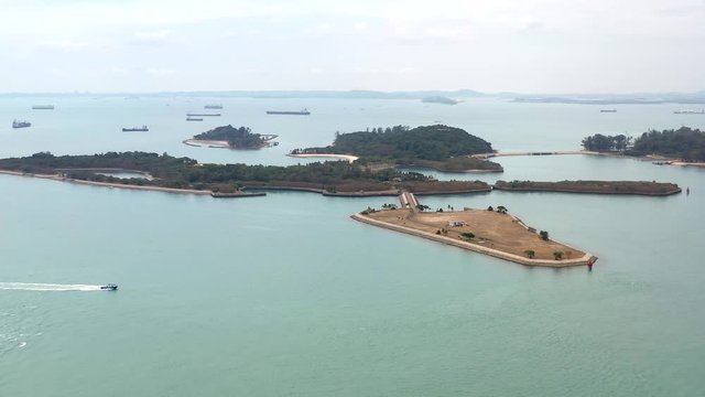 Aerial, drone shot, towards the Lazarus, St John and Seringat islands, a boat on the sea, on a sunny day, at a coast of Singapore, Asia
