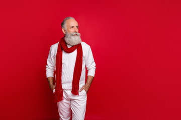 Trendy senior man with grey hair and beard santa like style wear warm knitted clothes isolated red...