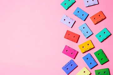 Painted audio cassettes on pastel pink background, copy space, top view. Retro musical background