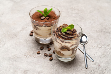 Classic tiramisu dessert in a glass cup on concrete background