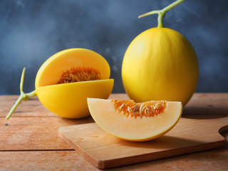 Fresh yellow melon fruit sliced with seed on wooden chopping board for a healthy eating concept.