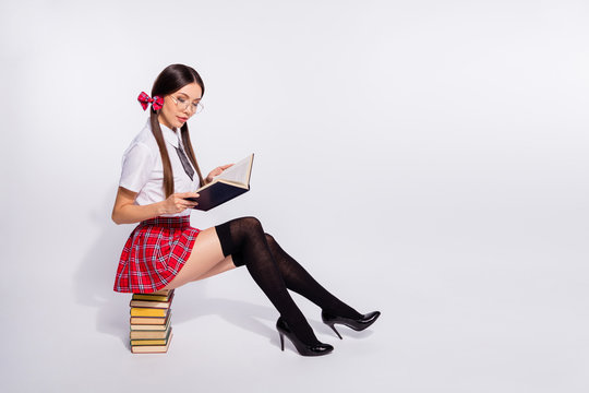Full length side profile body size photo beautiful she her teacher sit reader book pile diligent student tails return study wear specs short red checkered costume pantyhose isolated white background