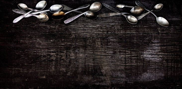 Vintage cutlery - spoons, forks and knives on an old wooden background.