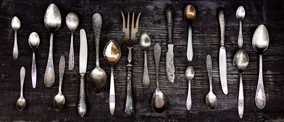 Vintage cutlery - spoons, forks and knives on an old wooden background.