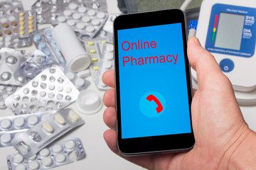 Modern smartphone in the hand of a person on the background of medicines, the concept of an online pharmacy.