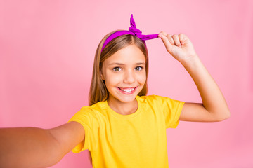 Self-portrait of her she nice attractive lovely winsome cheerful cheery pre-teen girl wearing yellow t-shirt fastening fixing head band isolated over pink pastel background